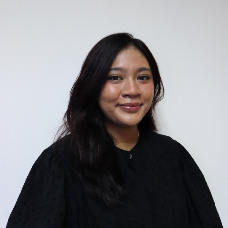 Professional woman with long dark hair, smiling in a black outfit against a plain white background.