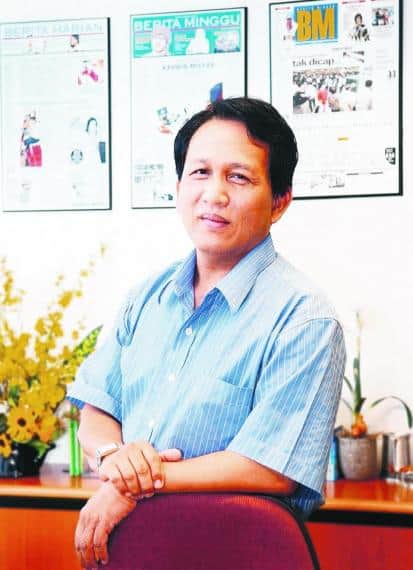 Expert man in office with newspaper headlines on wall behind, professional workspace, journalism or media environment, RIMA branding.