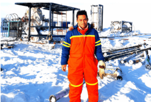 Snowy industrial site with worker in safety gear in winter landscape.