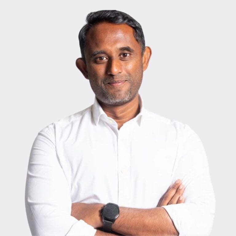 Confident professional man in white shirt with crossed arms, minimalist background, representing leadership and expertise.