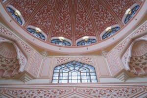 Delicate Islamic architecture with intricate patterns and stained glass domed ceiling.