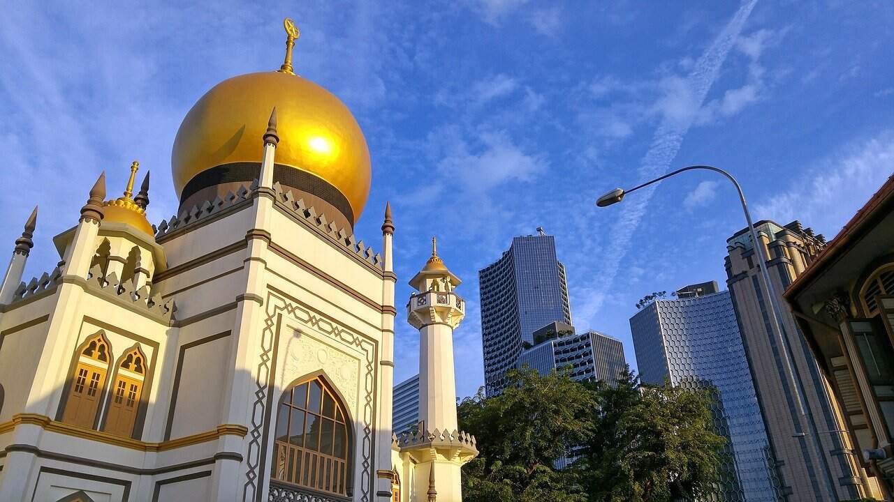 Golden-domed mosque with modern skyscrapers in Kuala Lumpur, Malaysia.